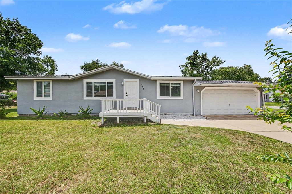 A single-story gray house with a white front door, small porch, and attached garage — 701 E WOODLAND STREET, BUNNELL, FL
