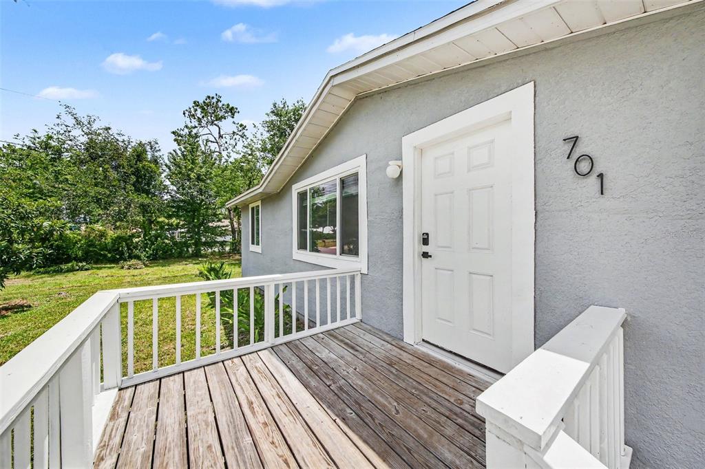 A wooden porch with white railings leads to the front door of a gray house — 701 E WOODLAND STREET, BUNNELL, FL