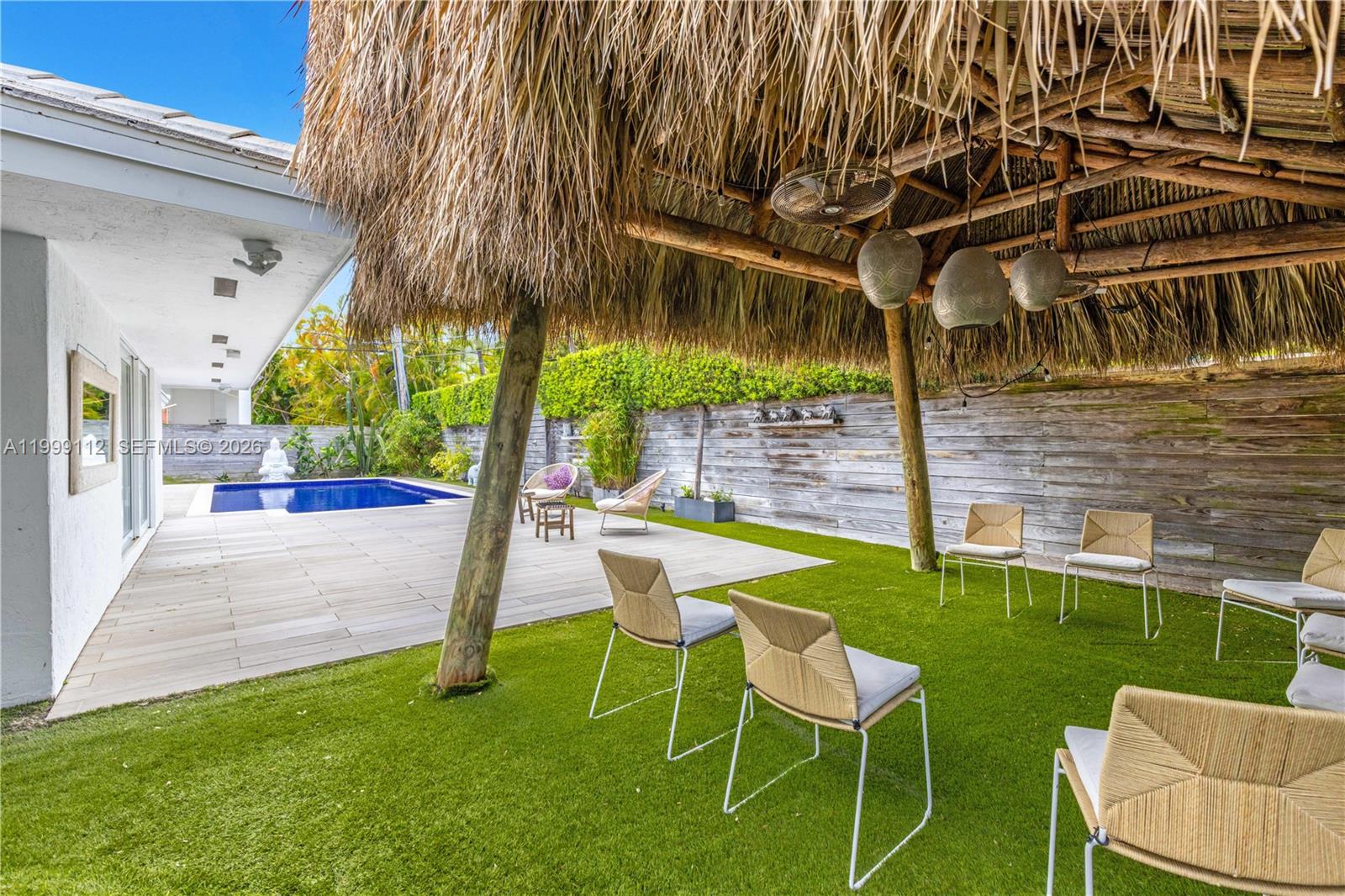 A backyard features a tiki hut, artificial turf, patio furniture, and a swimming pool — 524 Warren Ln, Key Biscayne FL 33149, KEY BISCAYNE, FL