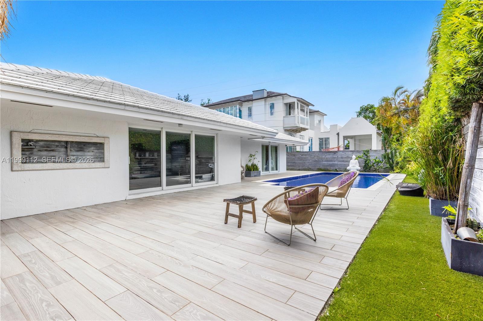 A white house exterior features a tiled patio, swimming pool, and two outdoor chairs — 524 Warren Ln, Key Biscayne FL 33149, KEY BISCAYNE, FL