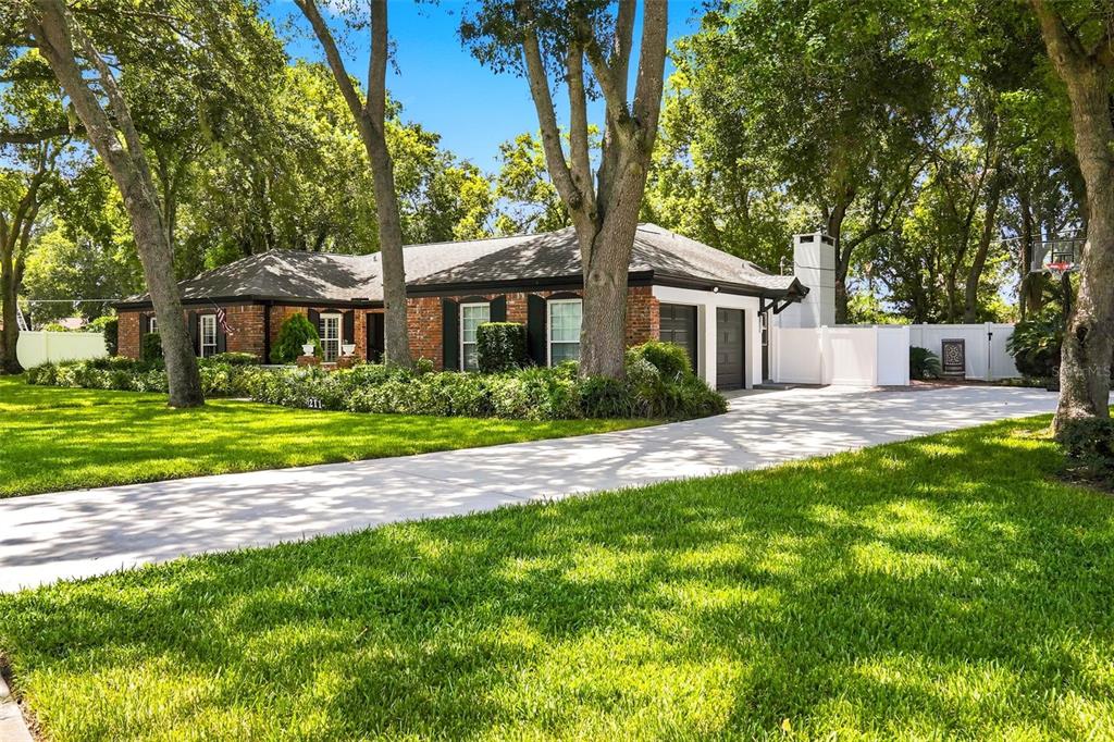 A single-story brick house with a concrete driveway and mature trees on a grassy lawn — 211 TALMEDA TRAIL, MAITLAND, FL