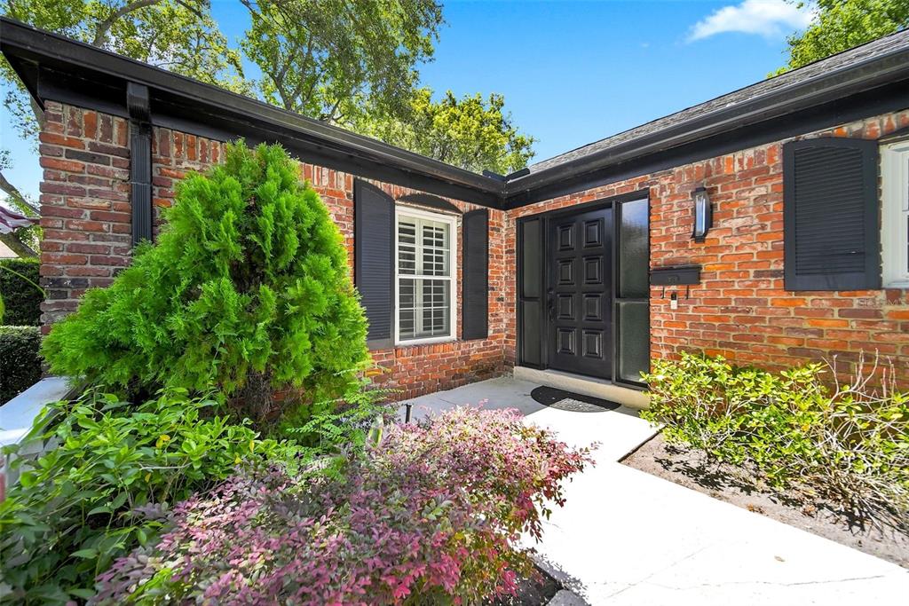 A brick house exterior features a black front door, dark shutters, and a landscaped walkway — 211 TALMEDA TRAIL, MAITLAND, FL