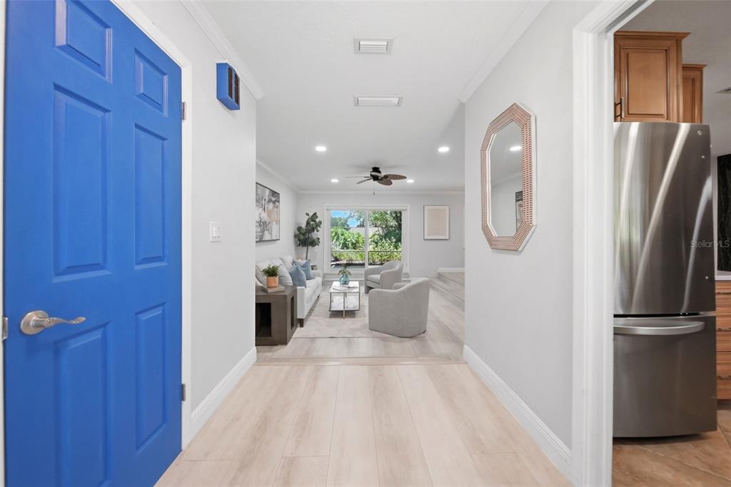 A hallway with light wood flooring leads into a living room with gray furniture — 211 TALMEDA TRAIL, MAITLAND, FL