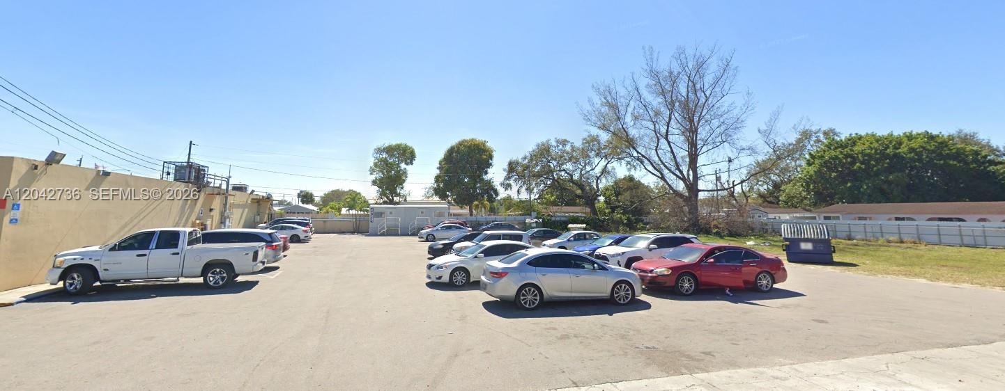 A paved parking lot with several parked cars sits beside a low-rise commercial building — 9360 NW 27th Ave, Miami FL 33147, MIAMI, FL