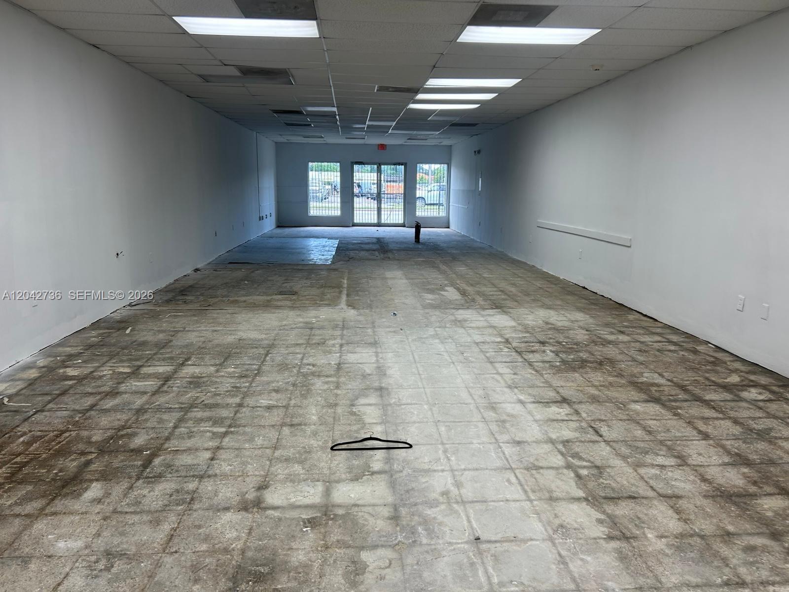 An empty commercial space features white walls, a drop ceiling, and a bare concrete floor — 9360 NW 27th Ave, Miami FL 33147, MIAMI, FL