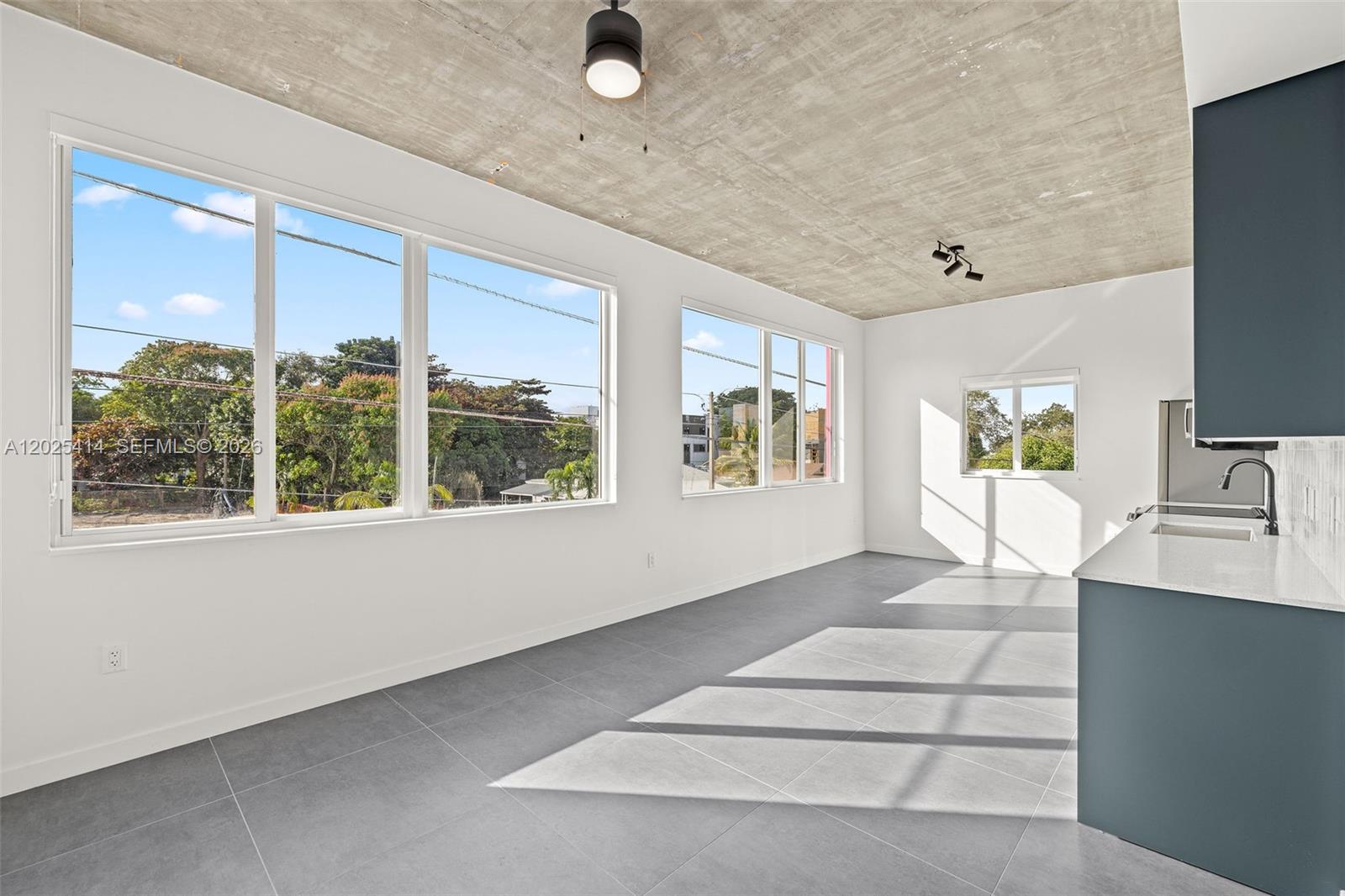 A modern kitchen and living area features a raw concrete ceiling and large windows — 315 NW 32 ST # 301, Miami FL 33127, MIAMI, FL