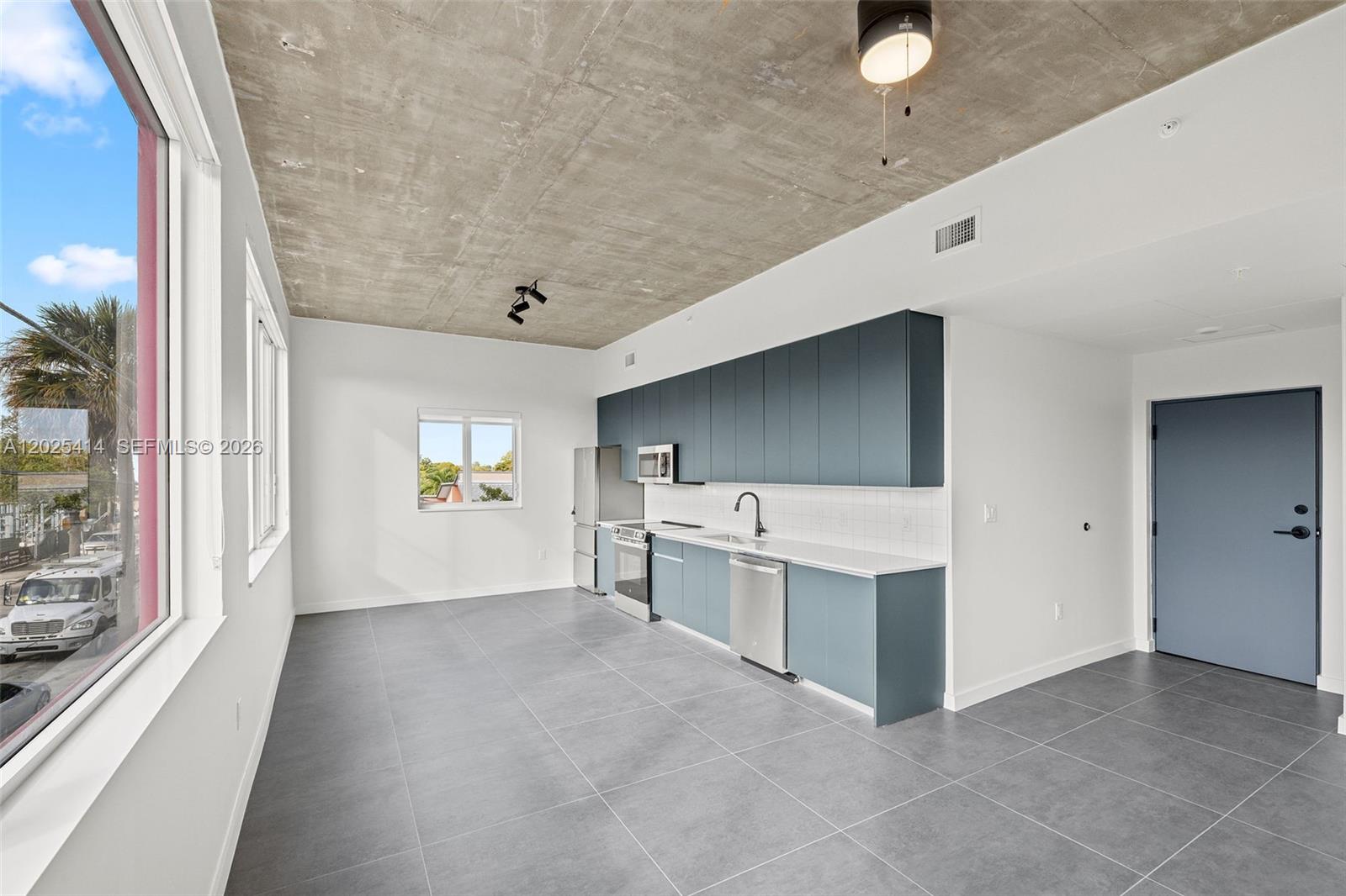 A modern kitchen features blue cabinetry, stainless steel appliances, and an exposed concrete ceiling — 315 NW 32 ST # 301, Miami FL 33127, MIAMI, FL