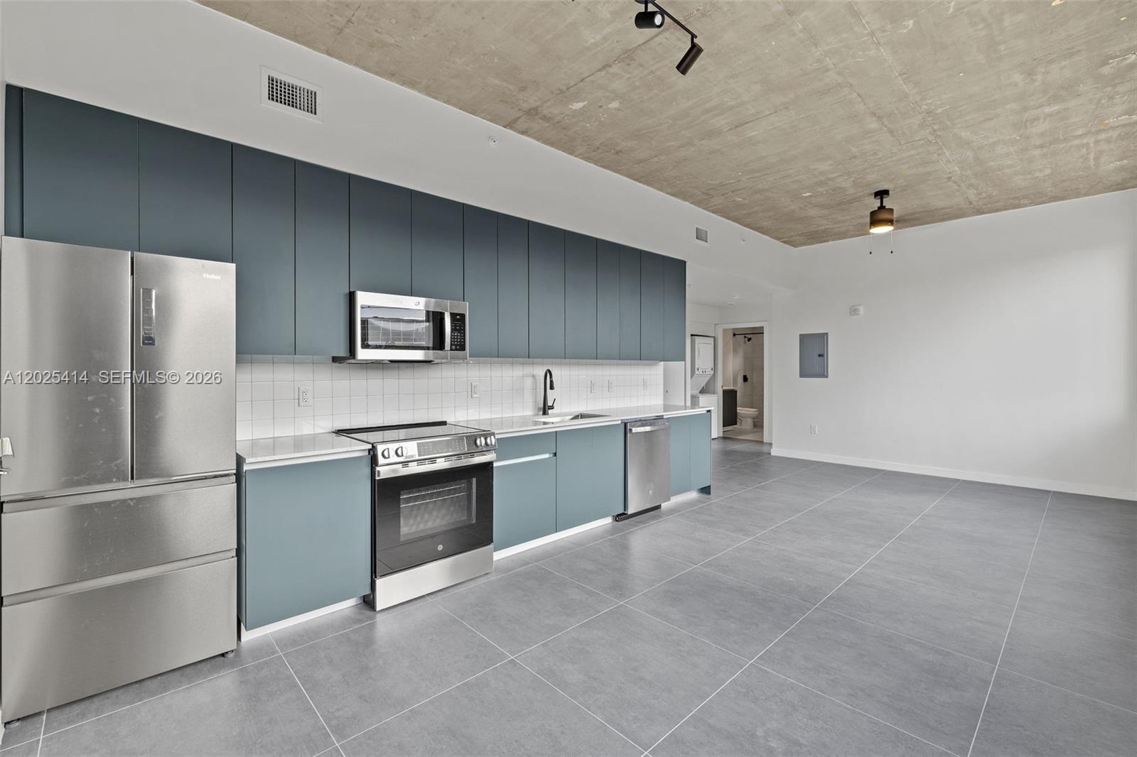 A modern kitchen features blue cabinets, stainless steel appliances, and an exposed concrete ceiling — 315 NW 32 ST # 301, Miami FL 33127, MIAMI, FL