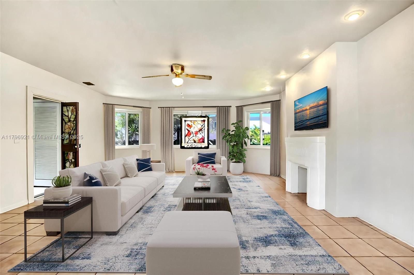 A bright living room features a white sofa, a coffee table, and a wall-mounted television — 326 S 14th Ave, Hollywood FL 33020, HOLLYWOOD, FL