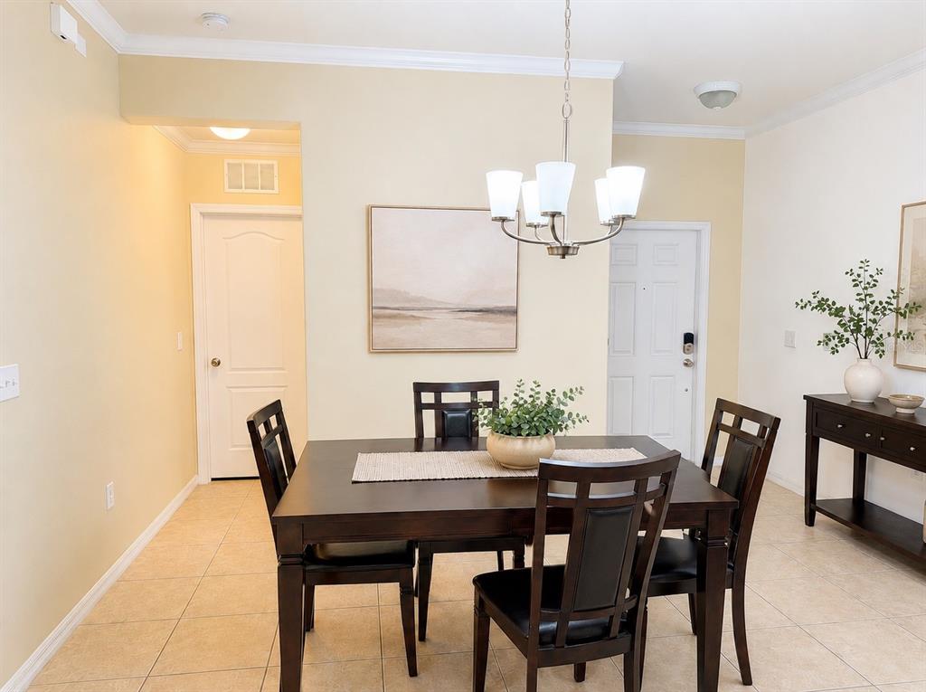 A dining room features a dark wood table, four chairs, and a chandelier — 9143 SAVANNAH AINSLEY LANE, ORLANDO, FL