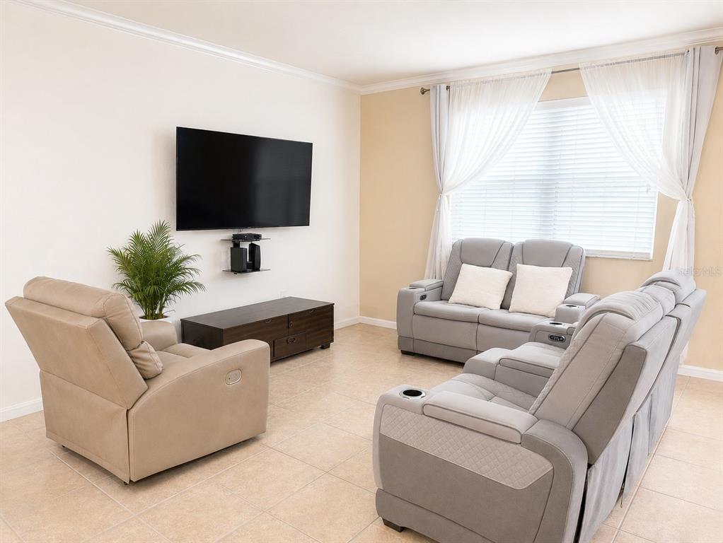 A living room features a wall-mounted television, a media console, a recliner, and two sofas — 9143 SAVANNAH AINSLEY LANE, ORLANDO, FL