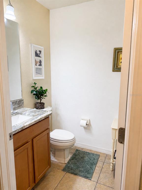 A small bathroom features a wood vanity, a white toilet, and tile flooring — 9143 SAVANNAH AINSLEY LANE, ORLANDO, FL