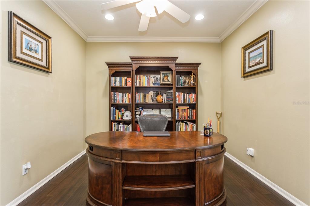 A home office features a large wooden desk, a bookshelf, and framed wall art — 1433 EMERALD HILL WAY, VALRICO, FL