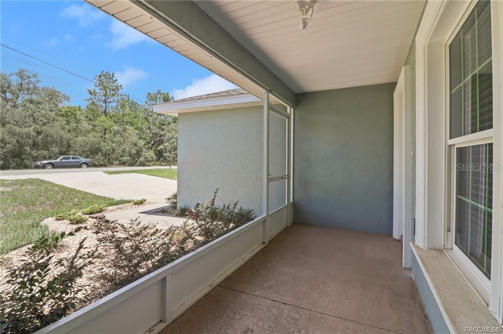 A covered, screened-in porch with a concrete floor and views of a driveway and trees — 10383 N G MARTINELLI BOULEVARD, CITRUS SPRINGS, FL