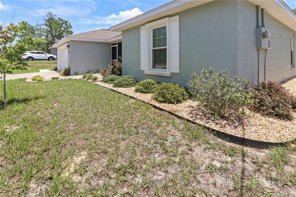 A light green house exterior features a front lawn, landscaping, and a white-trimmed window — 10383 N G MARTINELLI BOULEVARD, CITRUS SPRINGS, FL
