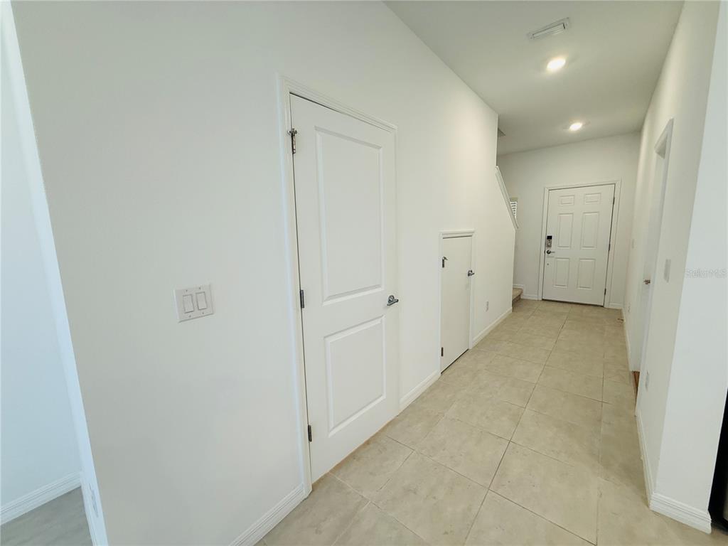 A hallway with tile flooring, white walls, a closet door, and a front entry door — 2264 PARAVANE WAY, WESLEY CHAPEL, FL