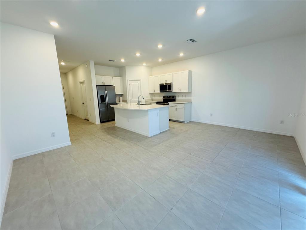 A modern kitchen features white cabinetry, a central island, and light-colored tile flooring — 2264 PARAVANE WAY, WESLEY CHAPEL, FL