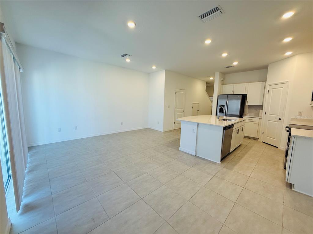 An open-concept kitchen and living area with white cabinets, a central island, and tile flooring — 2264 PARAVANE WAY, WESLEY CHAPEL, FL