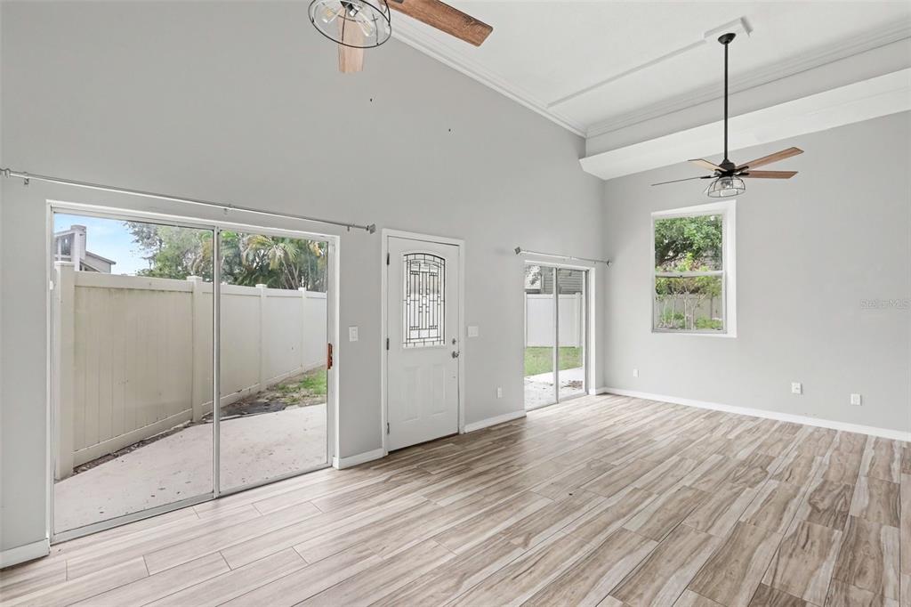 A living and dining area with high ceilings, sliding glass doors, and modern furniture — 9548 ORANGE VALLEY COURT, TAMPA, FL