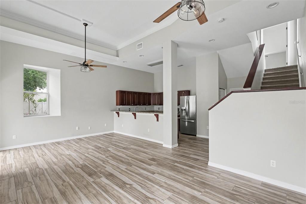 A bright living room features wood-look tile flooring, vaulted ceilings, two ceiling fans, and sliding doors — 9548 ORANGE VALLEY COURT, TAMPA, FL