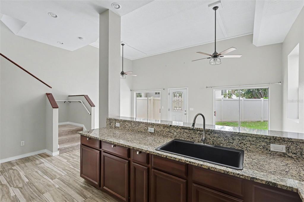 A kitchen with dark wood cabinets, granite countertops, stainless steel appliances, and wood-look tile flooring — 9548 ORANGE VALLEY COURT, TAMPA, FL