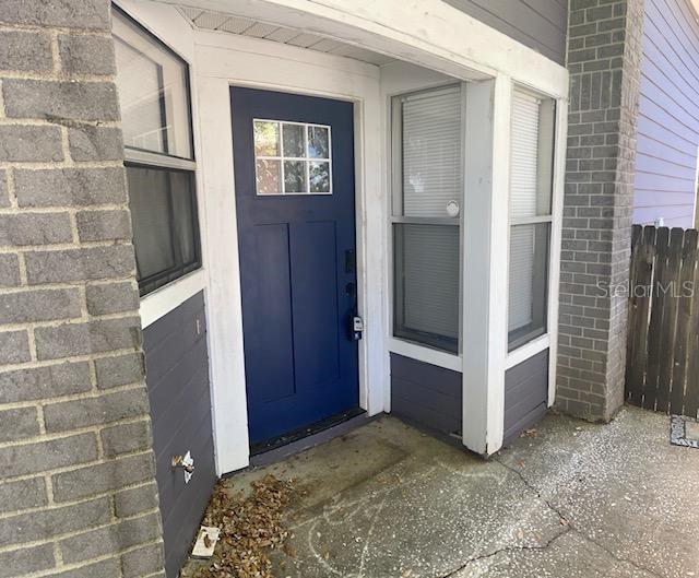 A blue front door with a window sits between brick walls and two windows — 245 ALSTON DRIVE, ORLANDO, FL