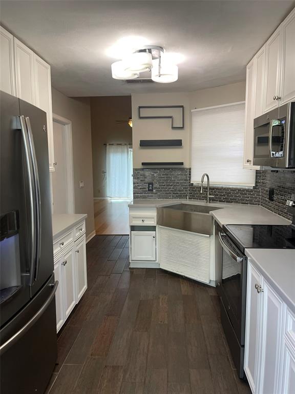 A kitchen with white cabinets, stainless steel appliances, a farmhouse sink, and dark wood flooring — 245 ALSTON DRIVE, ORLANDO, FL