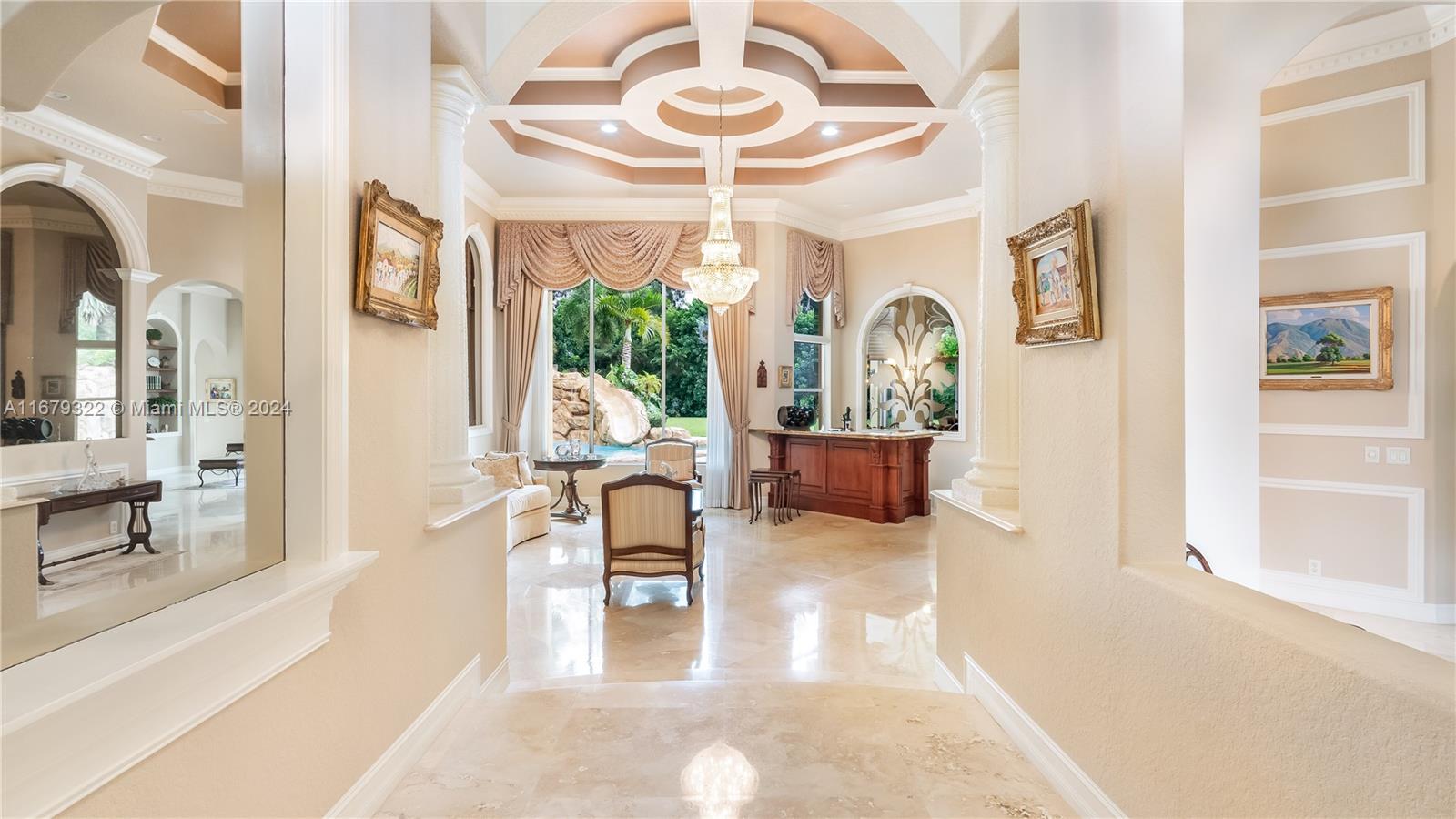 A formal living room features a coffered ceiling, crystal chandelier, marble floors, and a bar — 12854 Stonebrook Dr, Davie FL 33330, DAVIE, FL
