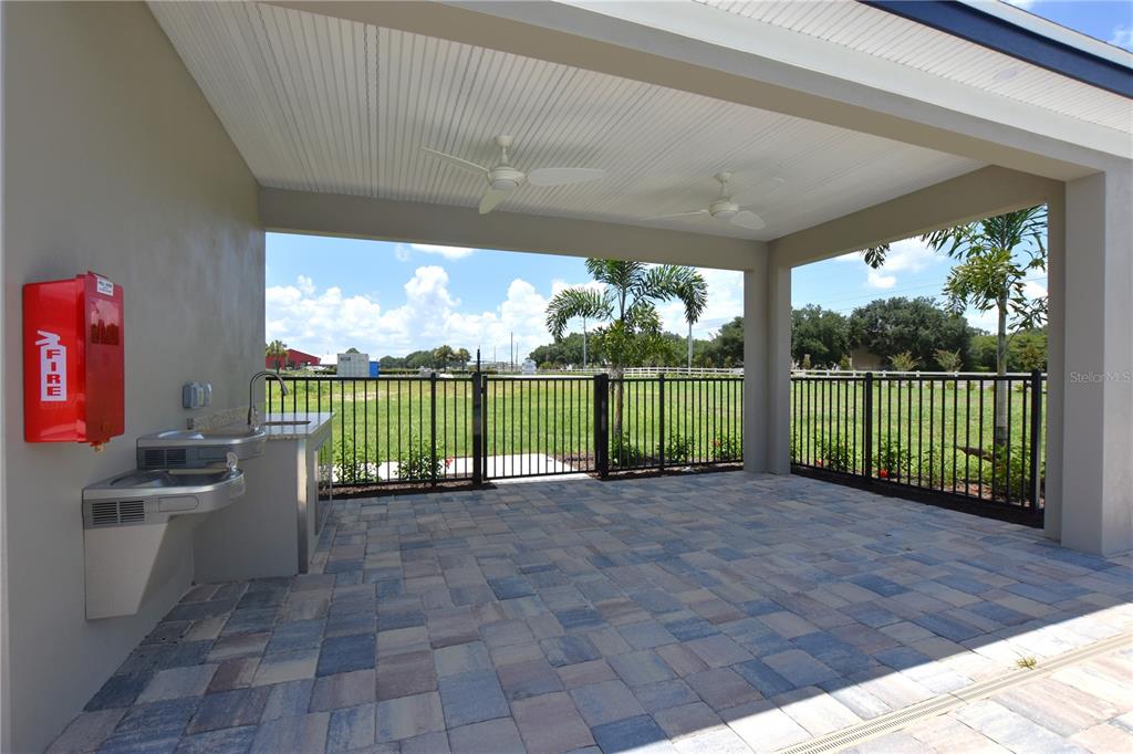A covered outdoor patio features a water fountain, a fire extinguisher, and ceiling fans — 3913 ACADEMIA AVENUE, LAKELAND, FL