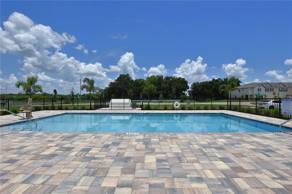 A rectangular swimming pool with a paver deck is enclosed by a black metal fence — 3913 ACADEMIA AVENUE, LAKELAND, FL