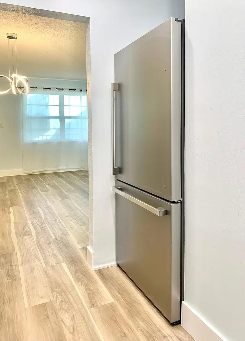 A stainless steel bottom-freezer refrigerator sits in a kitchen alcove next to a living area — 2850 NE 14th Street # 306b, Pompano Beach FL 33062, POMPANO BEACH, FL