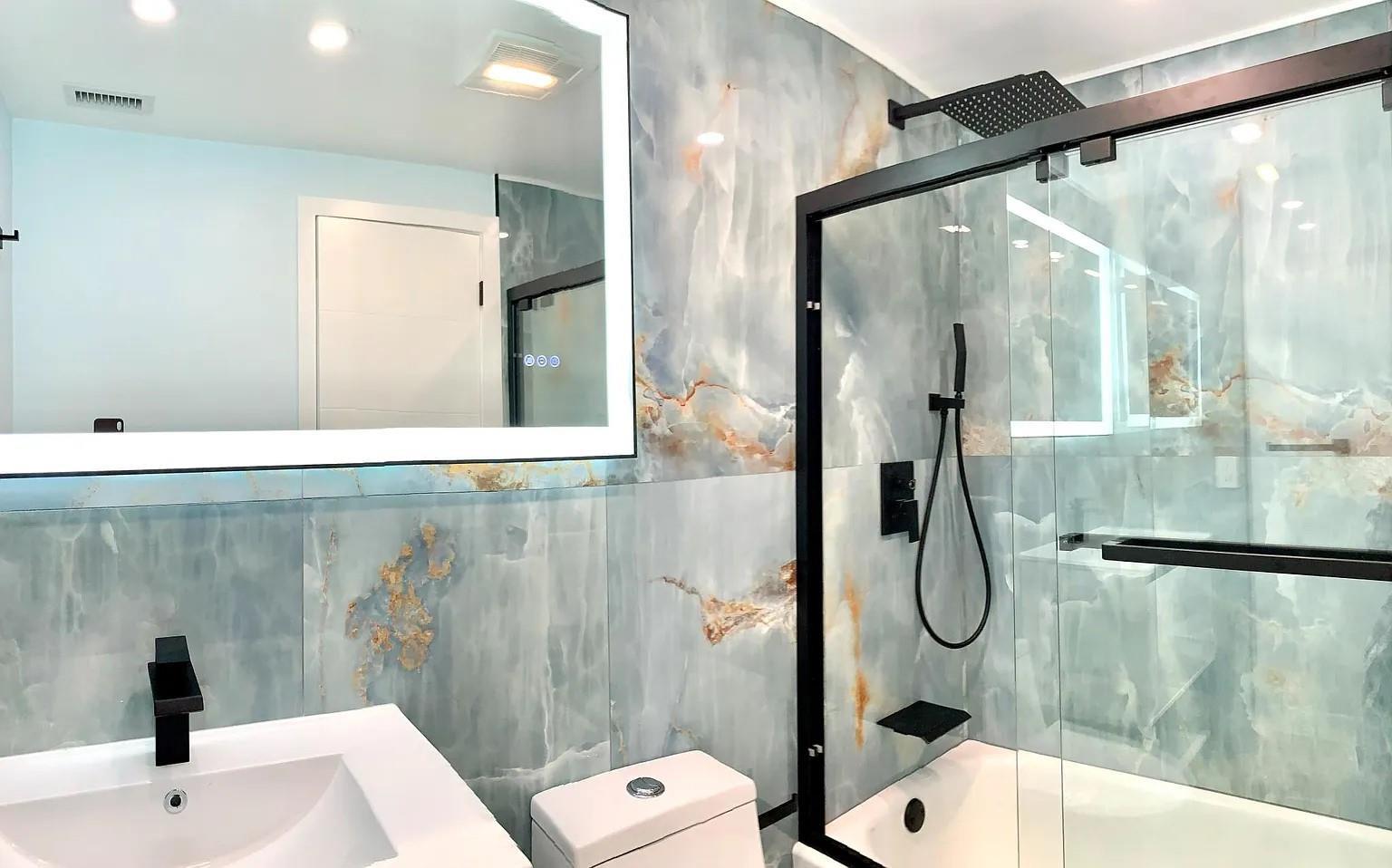 A bathroom features blue marble-style wall tiles, a black-framed shower, and a backlit vanity mirror — 2850 NE 14th Street # 306b, Pompano Beach FL 33062, POMPANO BEACH, FL