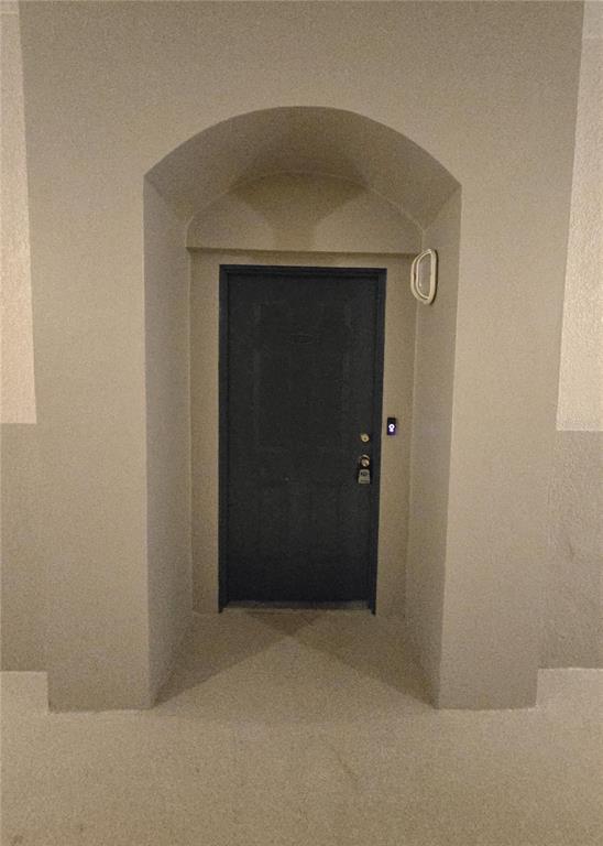 A dark front door is recessed within an arched entryway in a beige stucco wall — 3001 LAUREL RUN LANE UNIT 203, KISSIMMEE, FL