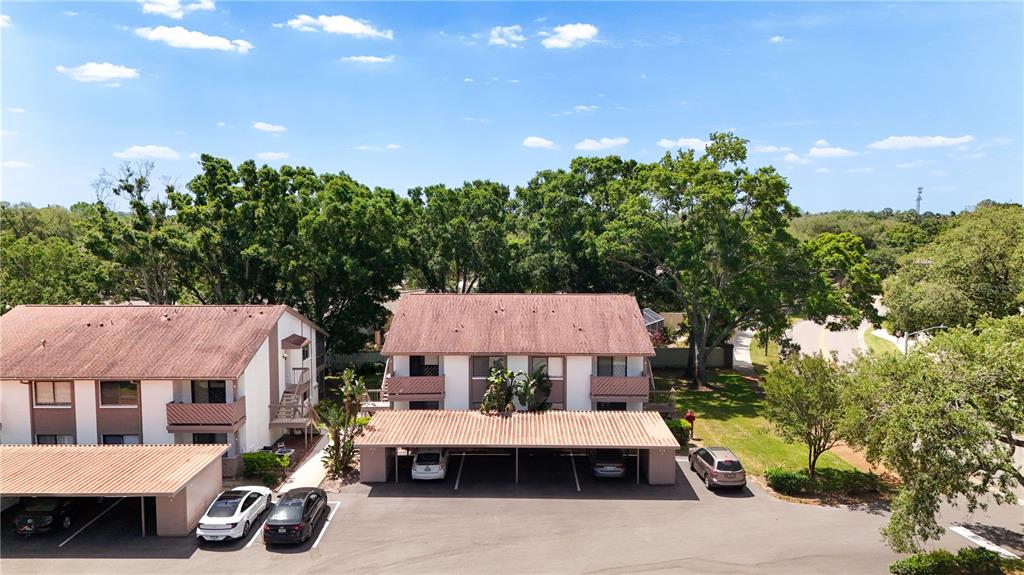 An aerial view shows two apartment buildings with covered parking spaces and several parked cars — 514 TABOR COURT UNIT C, SAFETY HARBOR, FL