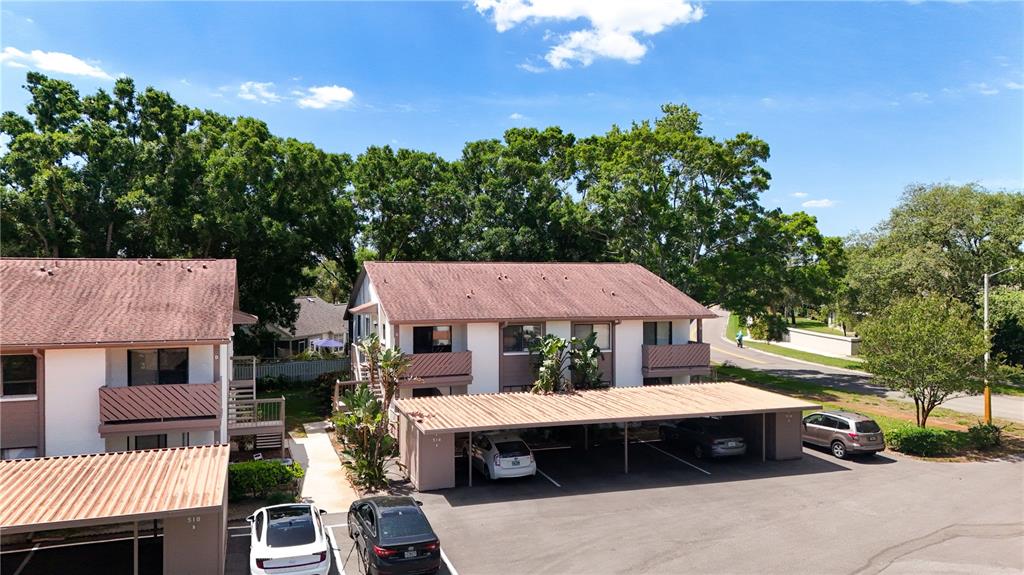An aerial view shows two multi-story apartment buildings with covered parking spaces and surrounding trees — 514 TABOR COURT UNIT C, SAFETY HARBOR, FL