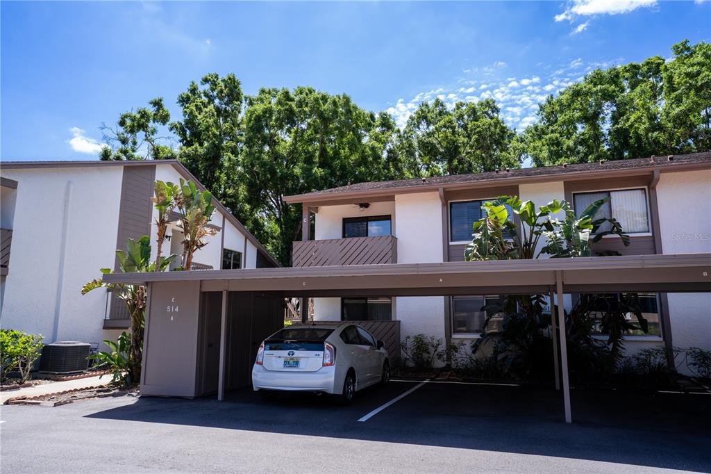 A white car is parked under a covered carport in front of a two-story apartment building — 514 TABOR COURT UNIT C, SAFETY HARBOR, FL