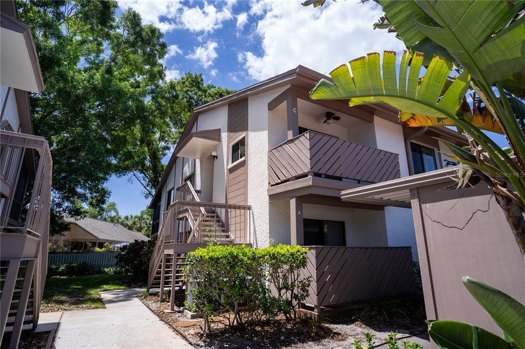Exterior view of a two-story apartment building with wooden balconies and an outdoor staircase — 514 TABOR COURT UNIT C, SAFETY HARBOR, FL
