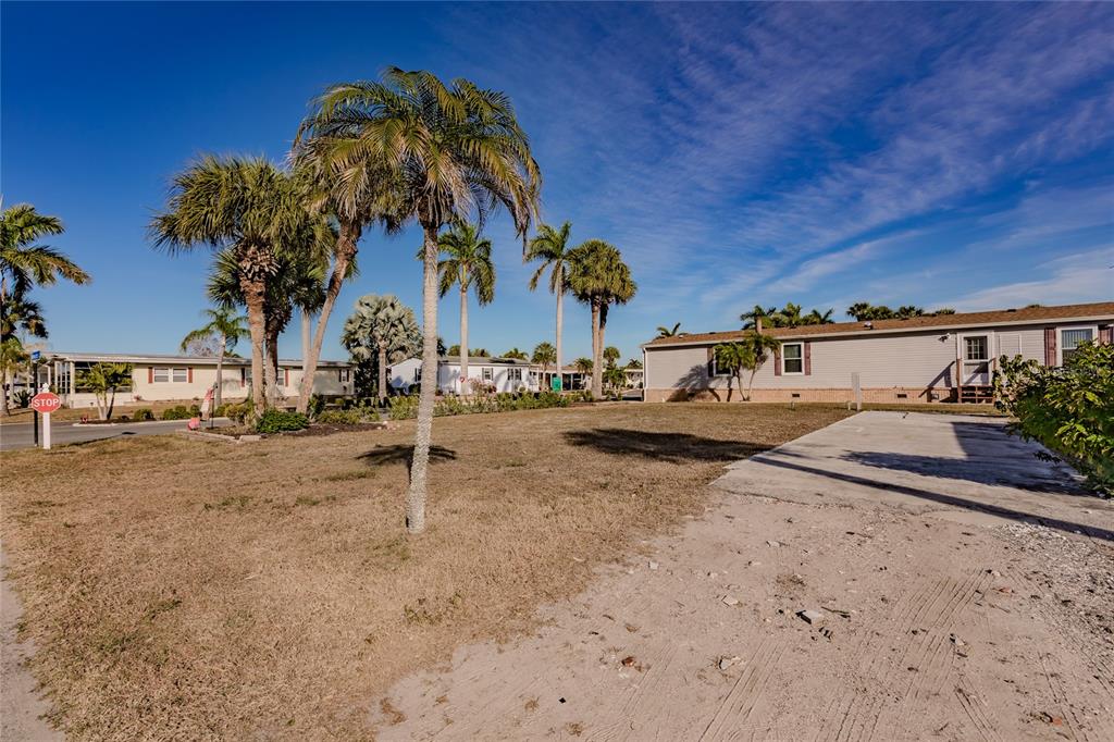 A vacant dirt lot sits in front of a manufactured home under a blue sky — 2100 KINGS HIGHWAY UNIT 28, PORT CHARLOTTE, FL