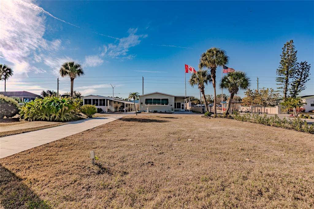 A single-story house with a driveway and palm trees sits on a large grassy lot — 2100 KINGS HIGHWAY UNIT 28, PORT CHARLOTTE, FL
