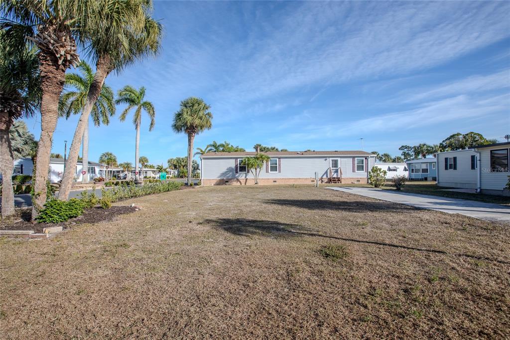 A wide, grassy lot features a single-story manufactured home and several palm trees — 2100 KINGS HIGHWAY UNIT 28, PORT CHARLOTTE, FL
