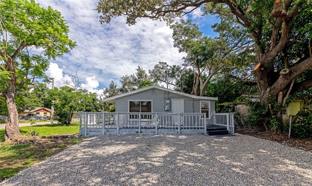 A gray, single-story house features a large wooden deck and a gravel driveway — 416 27TH AVENUE W, BRADENTON, FL