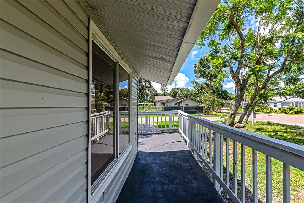 A covered porch with light gray siding, a dark floor, and a white wooden railing — 416 27TH AVENUE W, BRADENTON, FL
