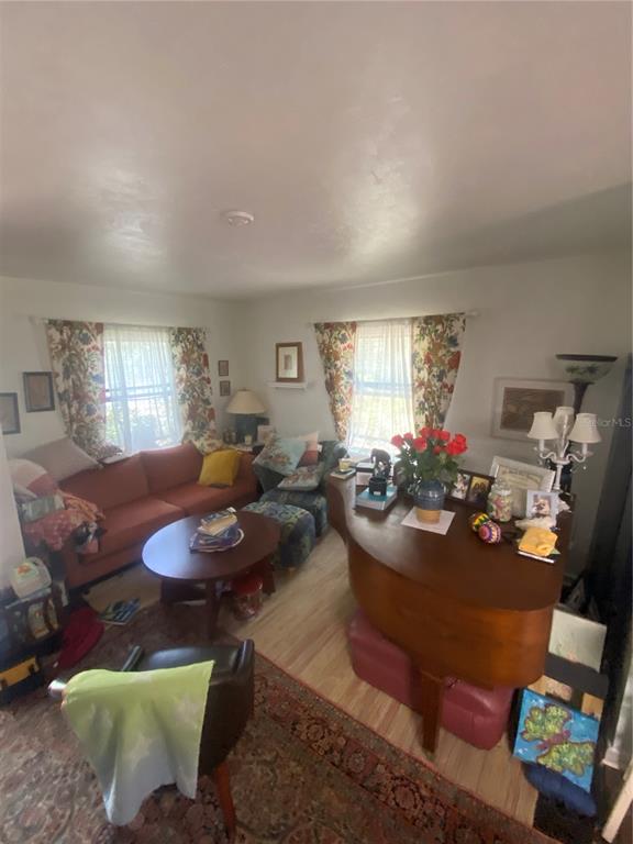 A living room features a piano, an orange sofa, a coffee table, and patterned curtains — 1231 NE 9TH STREET W, GAINESVILLE, FL