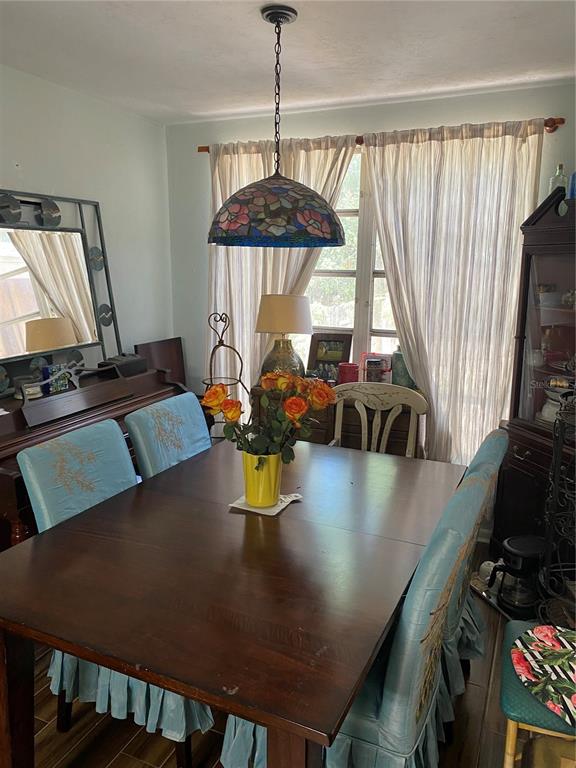 A dining room features a wooden table, blue slipcovered chairs, and a stained-glass pendant light — 1231 NE 9TH STREET W, GAINESVILLE, FL