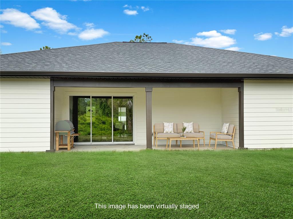 A covered patio with outdoor furniture and a grill sits behind a house with white siding — 73 BARSTOW STREET, PORT CHARLOTTE, FL