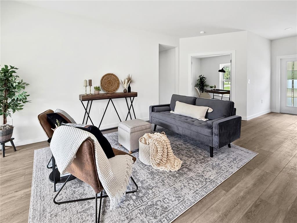 A living room features a gray sofa, two brown chairs, and a console table on wood-look flooring — 73 BARSTOW STREET, PORT CHARLOTTE, FL