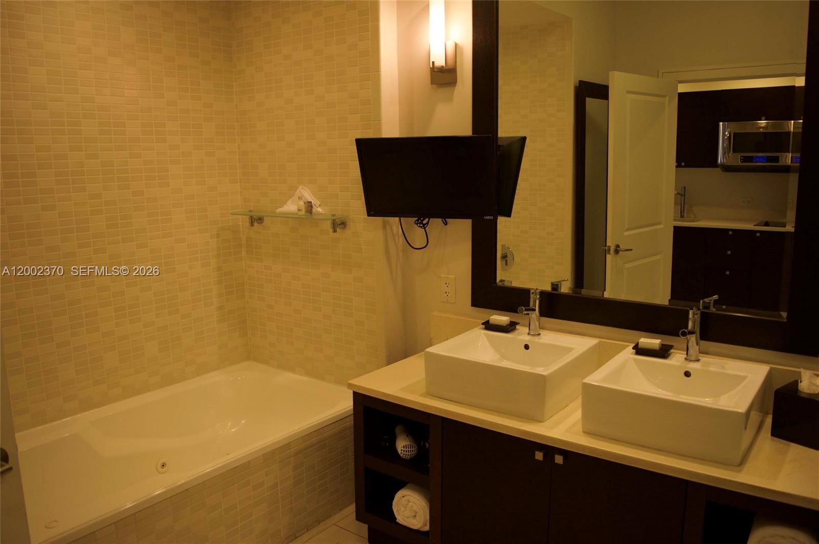 A bathroom features a soaking tub, double vessel sinks, and a wall-mounted television — 5300 NW 87th Ave # 809, Doral FL 33178, DORAL, FL