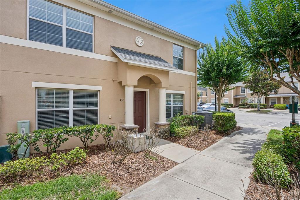 A two-story tan stucco building with a covered entryway and a concrete walkway — 450 CARINA CIRCLE, SANFORD, FL