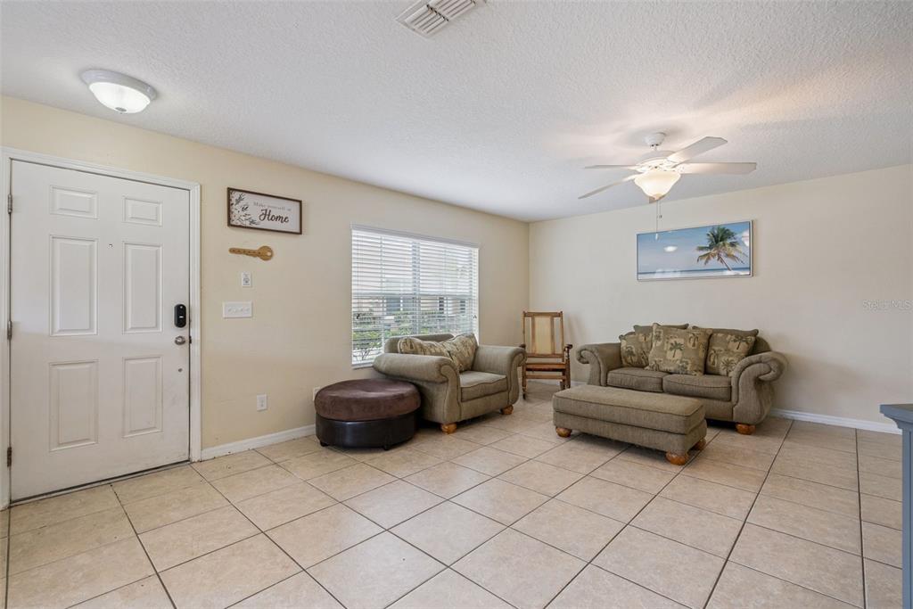 A living room with tile flooring, a front door, a window, and beige furniture — 450 CARINA CIRCLE, SANFORD, FL