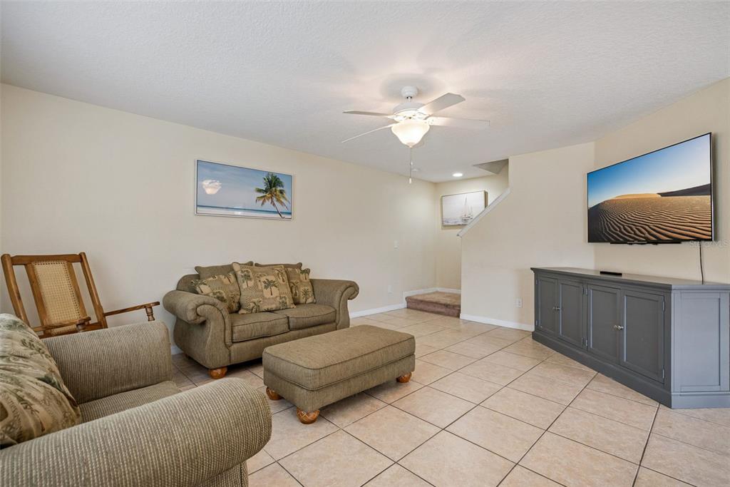 A living room features tile flooring, a beige sofa, a matching ottoman, and a television — 450 CARINA CIRCLE, SANFORD, FL